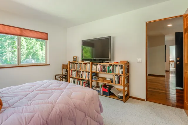 a bedroom with bed and a flat tv screen on dresser