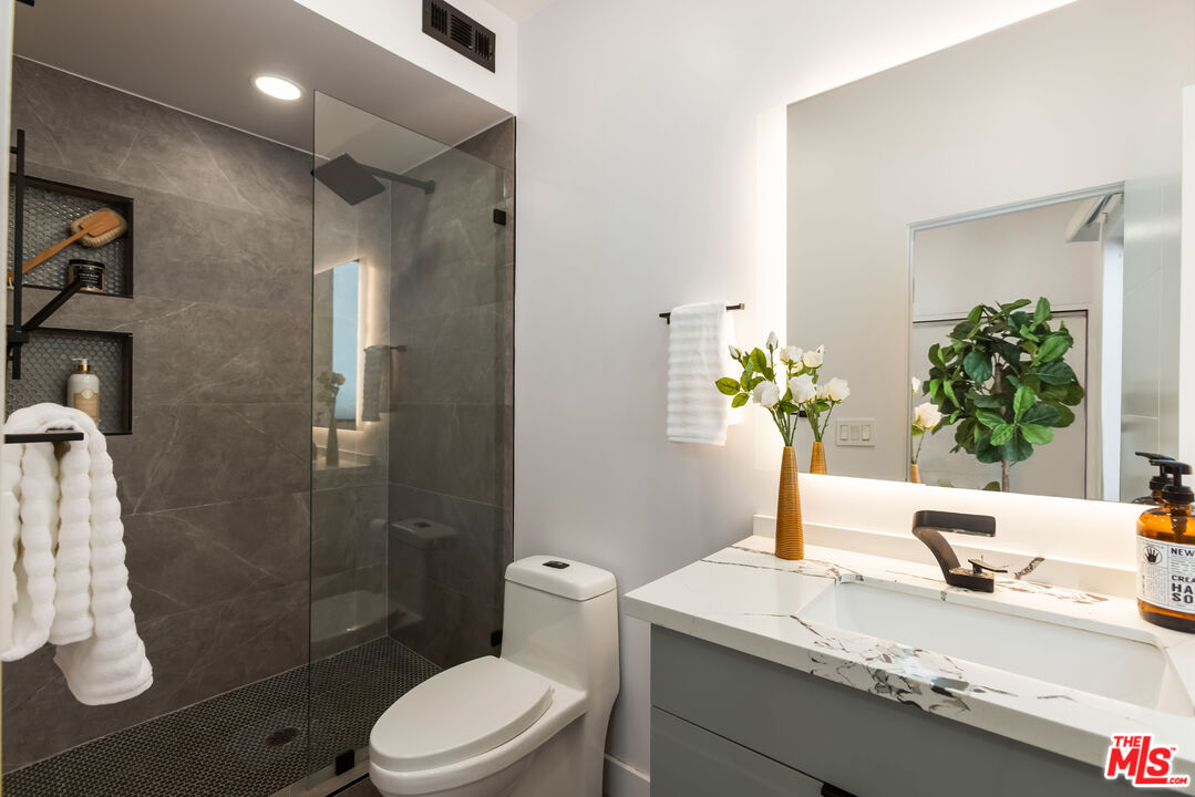 1210 North Kings Road, Unit 101 West Hollywood, CA 90069 - Photo 26 of 32 a bathroom with a granite countertop sink a toilet and shower