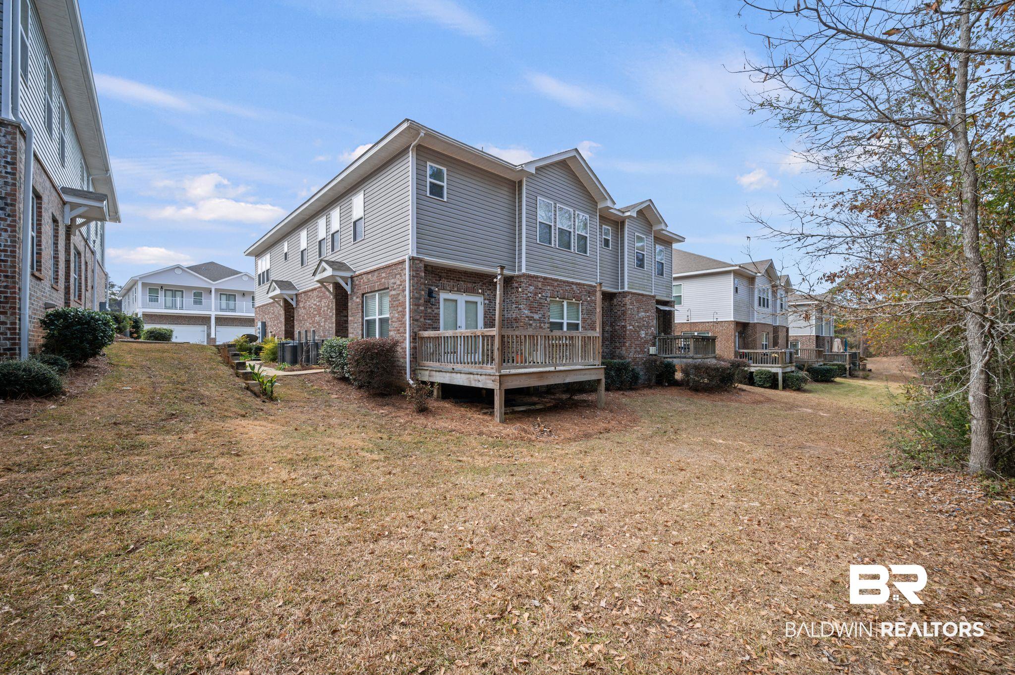6903 Spaniel Drive, Unit B Spanish Fort, AL 36527 - Photo 21 of 28 Rear view of house with a residential view, brick siding, a lawn, and a wooden deck