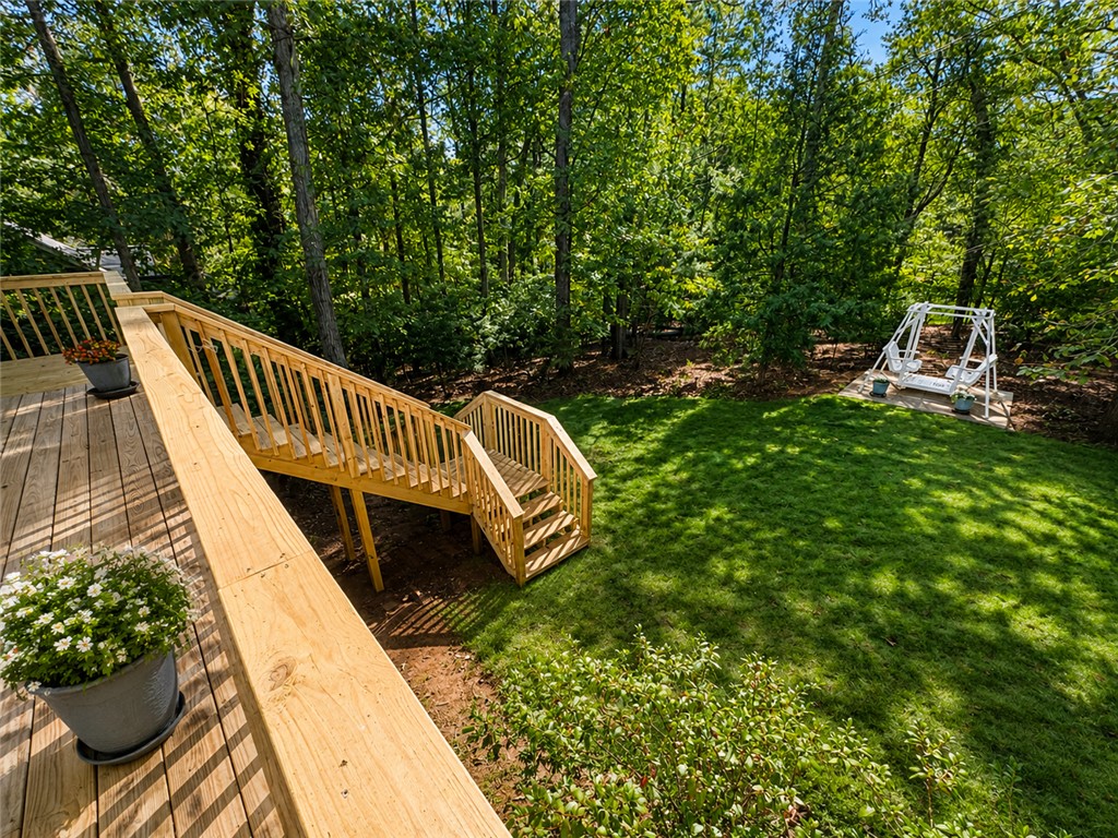 222 Terrace Drive Anderson, SC 29621 - Photo 25 of 37 A spacious wood deck and staircase descend to a verdant lawn, backed by a lush forest and featuring a charming swing.