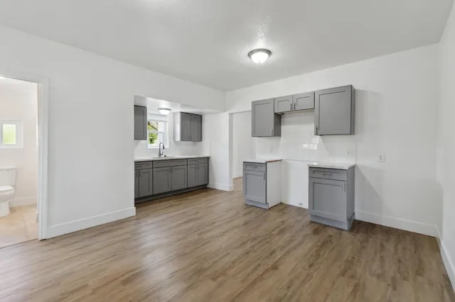 a kitchen with white cabinets and wooden floor