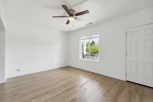 an empty room with wooden floor and windows