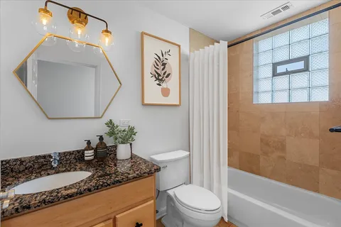 a bathroom with a granite countertop sink mirror vanity and toilet