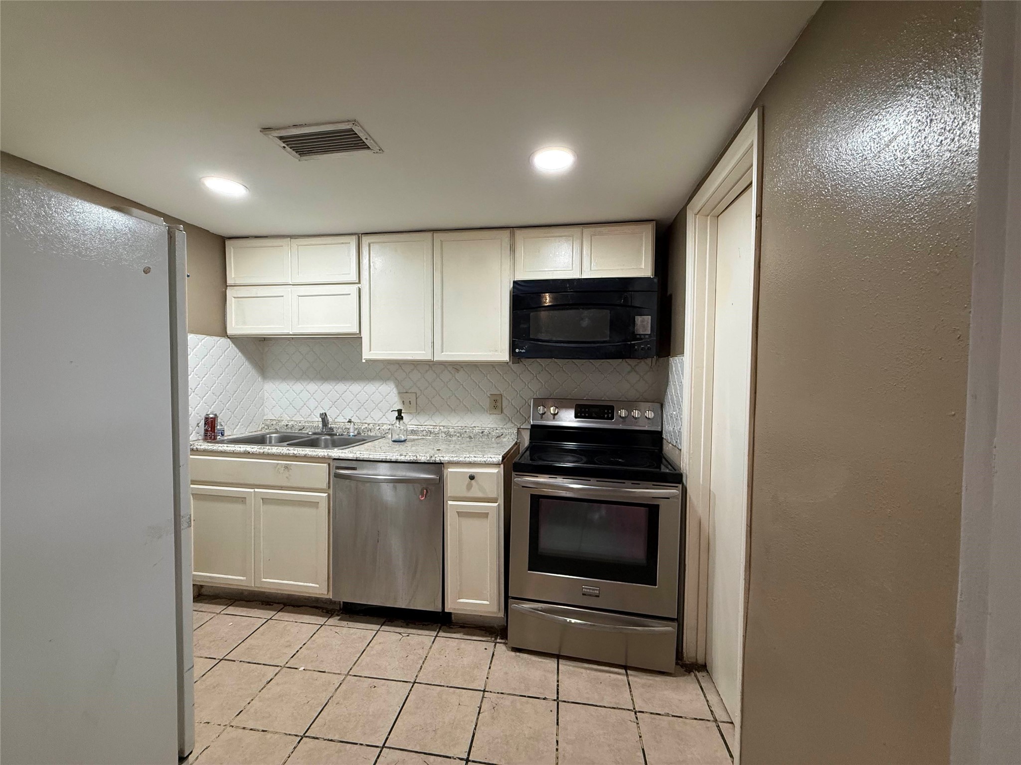 7047 Bissonnet Street, Unit 70 Houston, TX 77074 - Photo 8 of 23 a kitchen with stainless steel appliances granite countertop a stove a microwave and a refrigerator