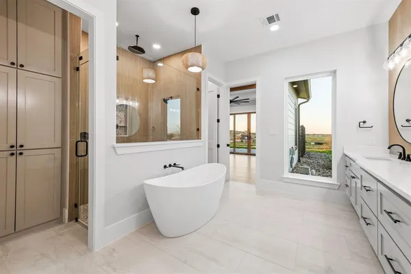 a spacious bathroom with a tub sink shower and mirror