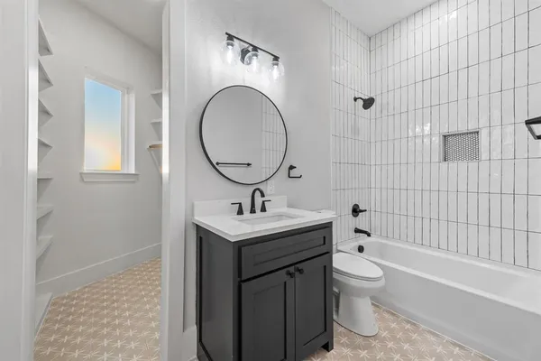 a bathroom with a granite countertop toilet a sink a mirror and bathtub