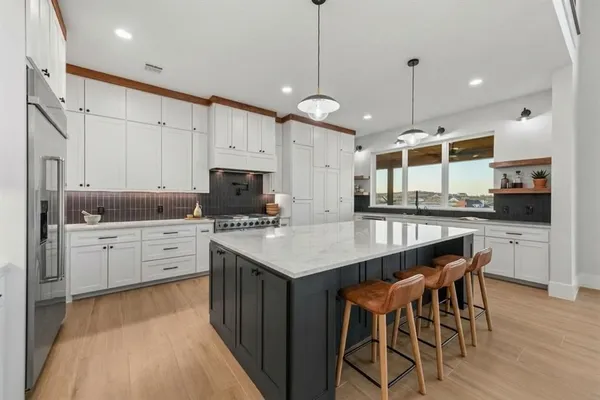 a kitchen with stainless steel appliances kitchen island granite countertop a table chairs sink and cabinets