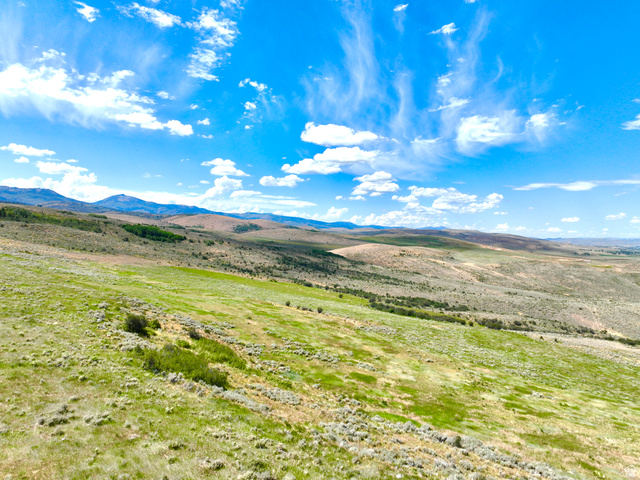 160 Dry Canyon St. Charles, ID 83272 - Photo 59 of 63 Expansive rolling landscape featuring varied green and brown vegetation, distant mountains, and a vibrant blue sky with scattered clouds