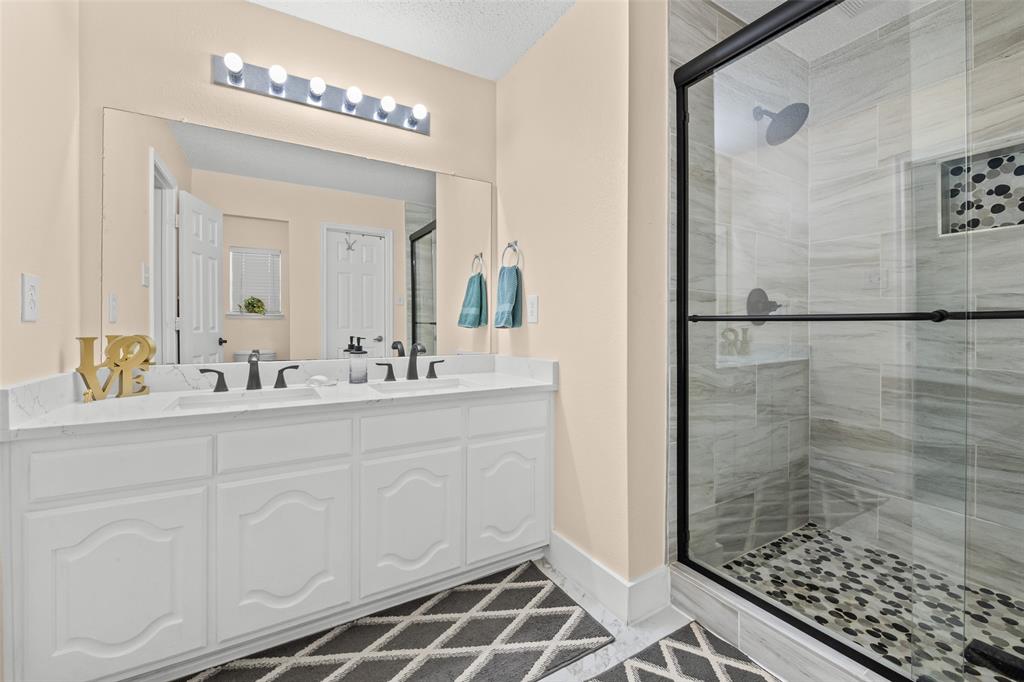 1424 Jacksons Run Greenville, TX 75402 - Photo 19 of 23 a bathroom with a double vanity sink a mirror and a shower