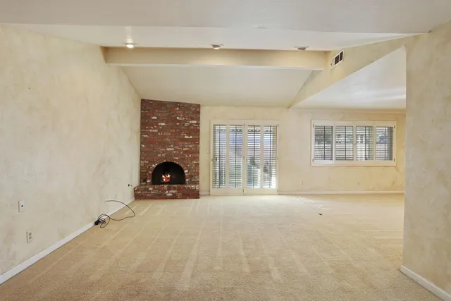a view of an empty room with a fireplace and a window