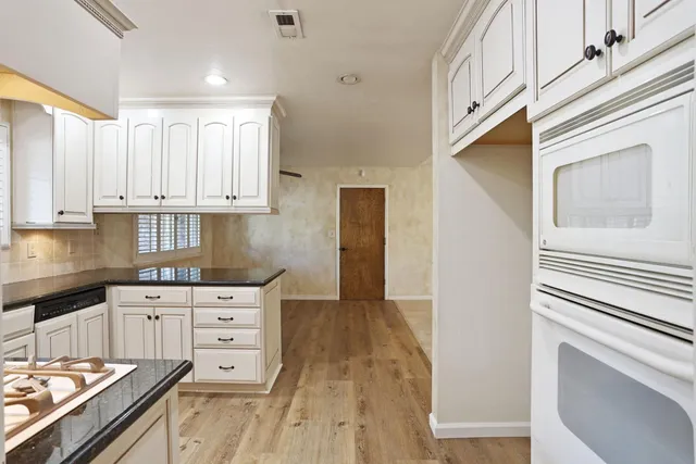 a kitchen with granite countertop a sink stove and cabinets
