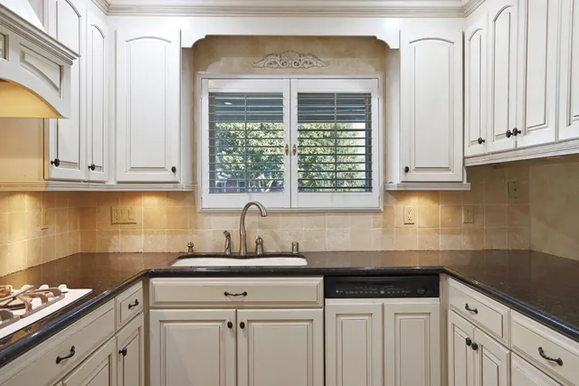 a kitchen with granite countertop white cabinets and a sink
