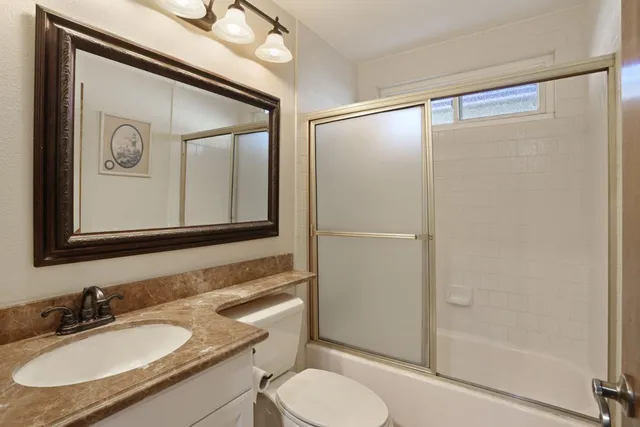 a bathroom with a granite countertop sink toilet and shower