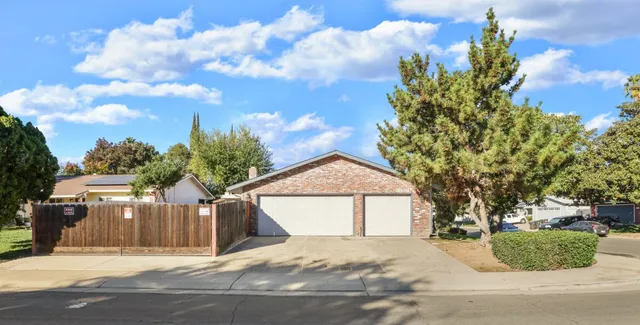 a front view of a house with a garden and trees