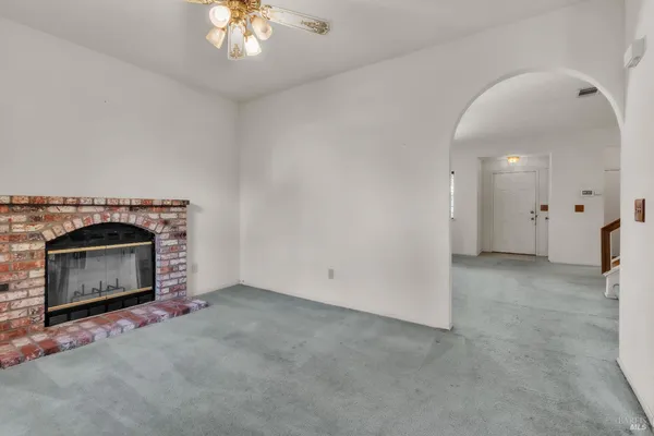 an empty room with a fireplace and chandelier