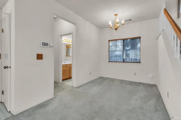 an empty room that has a chandelier fan and a dining table