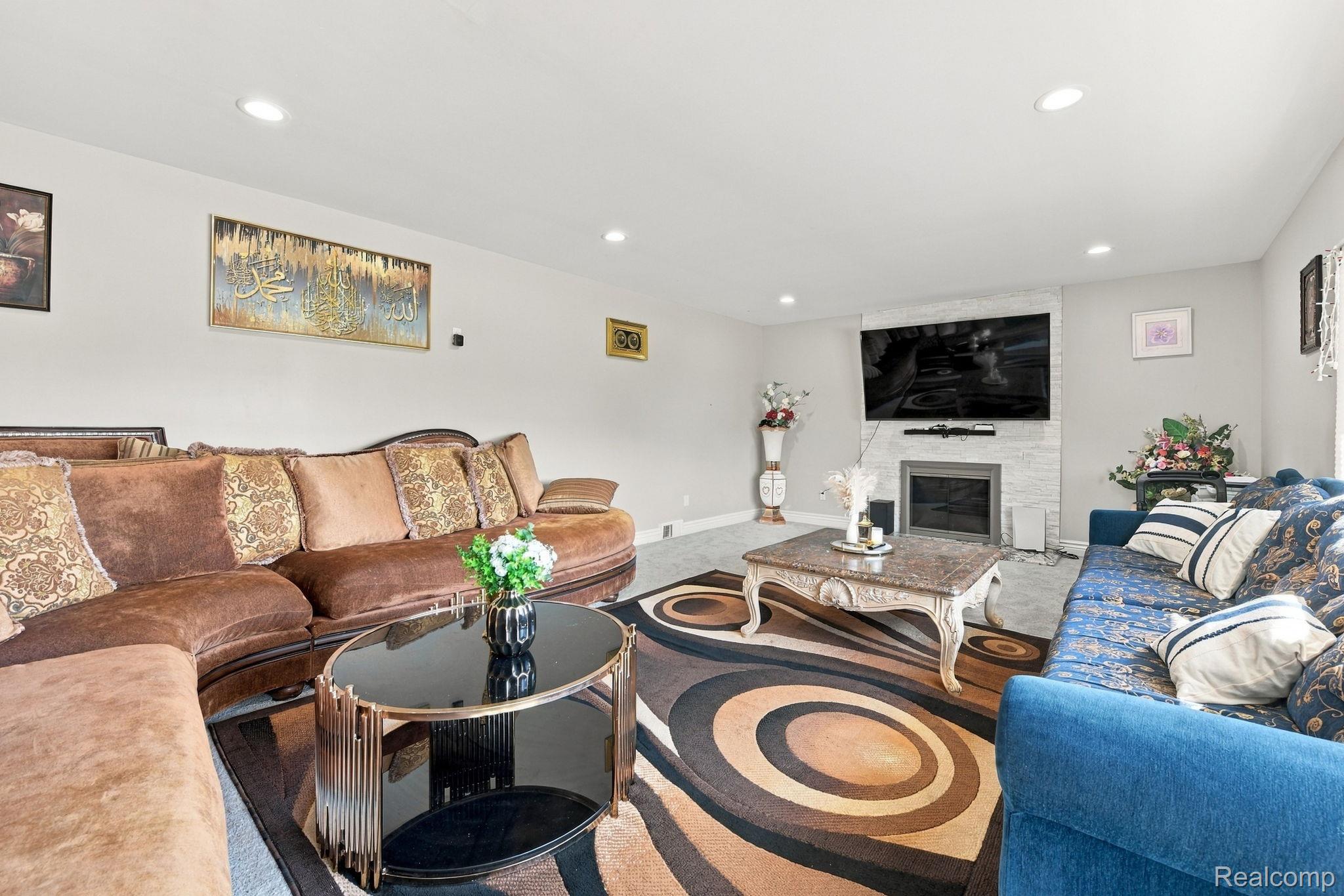 5353 18 Mile Road Sterling Heights, MI 48314 - Photo 11 of 53 Recessed lighting, fireplace with white stacked stone surround, wall-mounted television, and light gray wall finish