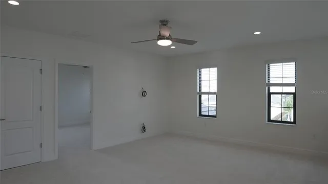 en empty room with windows and ceiling fan