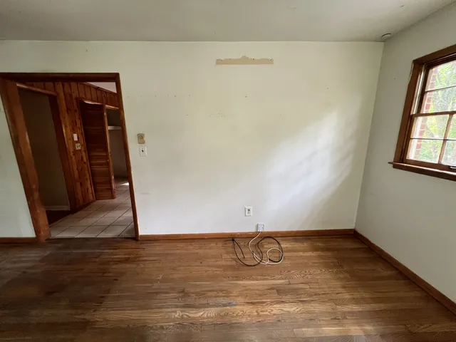 an empty room with wooden floor and window