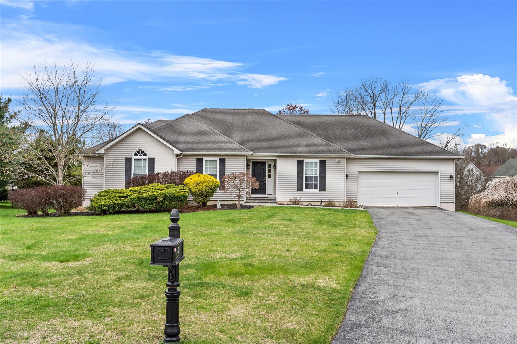 Ranch-style home featuring a front yard, an attached garage, a shingled roof, and aphalt driveway