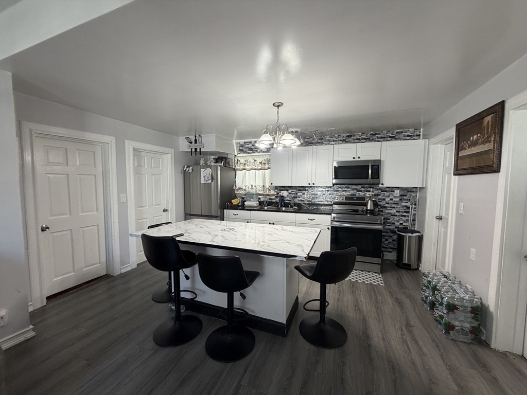 28-32 Chester Street Lawrence, MA 01843 - Photo 5 of 30 a kitchen with kitchen island stainless steel appliances a dining table chairs stove and sink