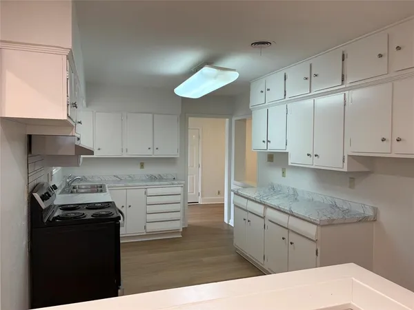 a kitchen with a sink dishwasher a stove and white cabinets
