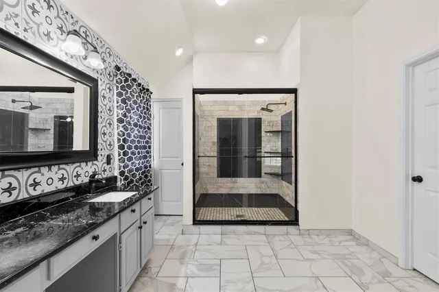 a bathroom with a granite countertop sink a mirror and shower