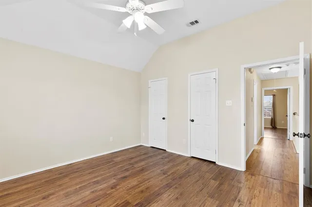 an empty room with wooden floor and ceiling fan