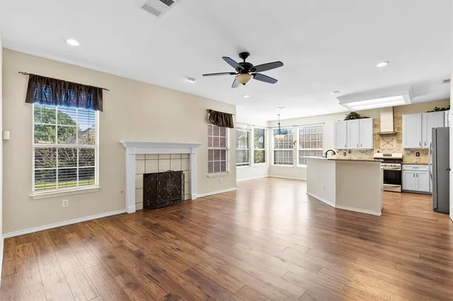 a view of an empty room with wooden floor and a kitchen