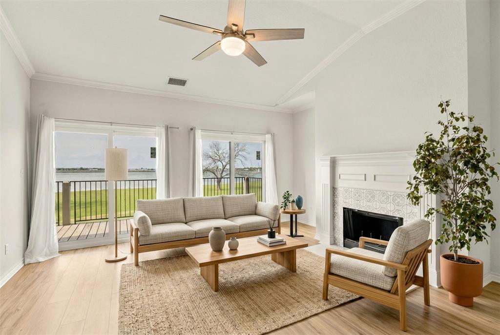 1916 Signal Ridge Place Rockwall, TX 75032 - Photo 2 of 32 Virtually staged Living room with vaulted ceiling, light wood finished floors, a ceiling fan, a fireplace, and ornamental molding