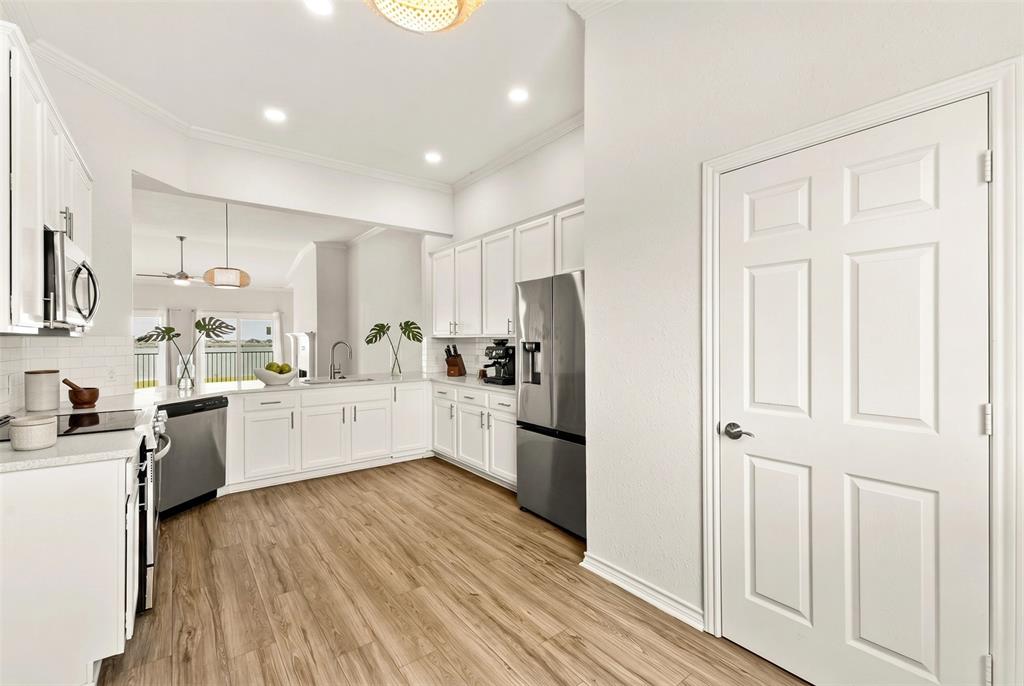 1916 Signal Ridge Place Rockwall, TX 75032 - Photo 6 of 32 Virtually staged Kitchen featuring white cabinetry, crown molding, stainless steel appliances, light wood-type flooring, and tasteful backsplash