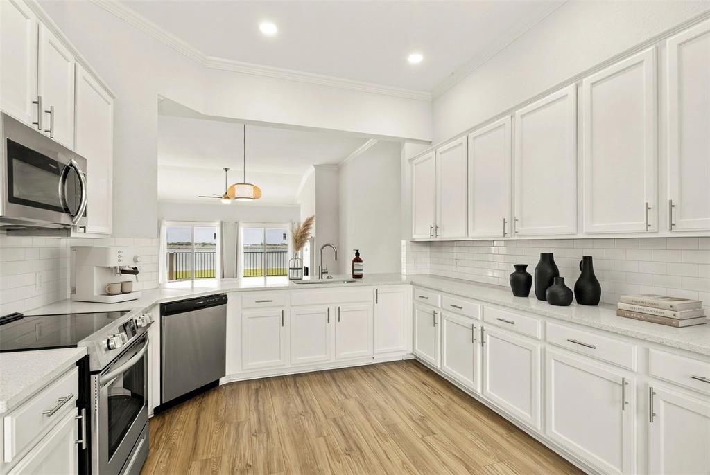 1916 Signal Ridge Place Rockwall, TX 75032 - Photo 7 of 32 Virtually staged Kitchen featuring stainless steel appliances, white cabinetry, ornamental molding, and backsplash