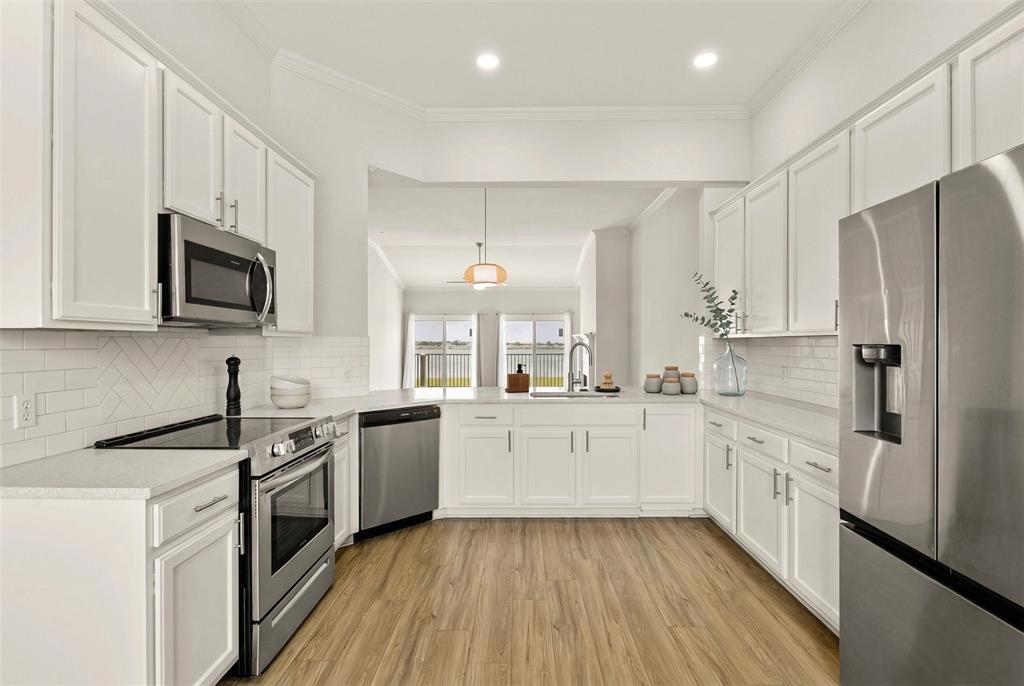 1916 Signal Ridge Place Rockwall, TX 75032 - Photo 8 of 32 Virtually stagedKitchen with stainless steel appliances, crown molding, white cabinets, light wood finished floors, and backsplash