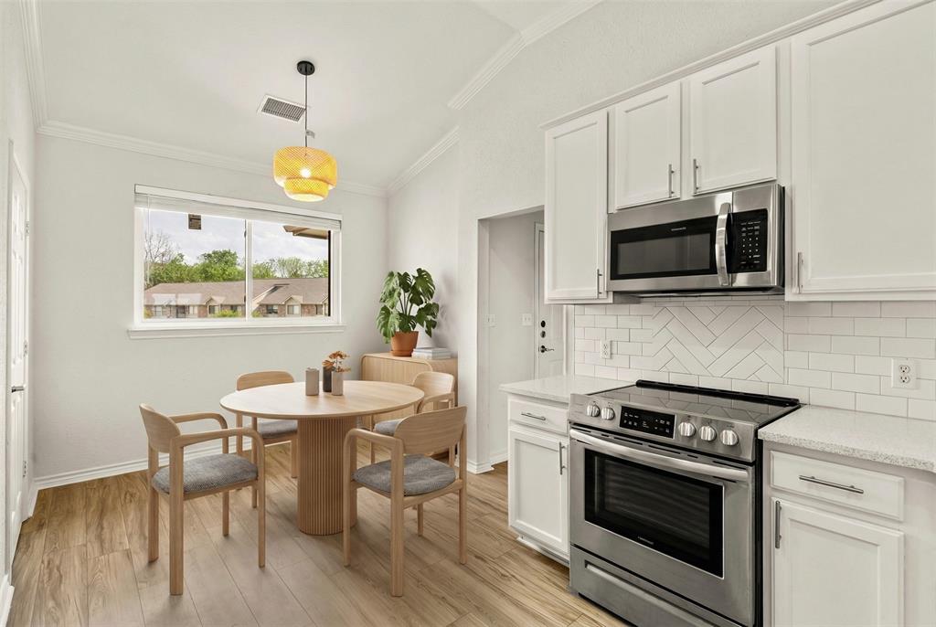 1916 Signal Ridge Place Rockwall, TX 75032 - Photo 10 of 32 Virtually staged Kitchen with stainless steel appliances, white cabinetry, decorative light fixtures, ornamental molding, and tasteful backsplash