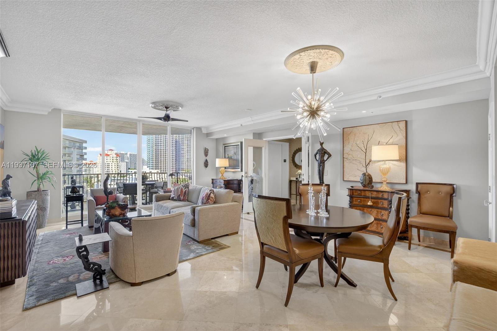 100 South Birch Road, Unit 1103F Fort Lauderdale, FL 33316 - Photo 27 of 80 Beautiful sputnik chandelier, Emtek crystal door hardware throughout unit, counter seating at kitchen. Crown molding. Open Concept living. Bright natural light. Floor to ceiling glass. Foyer from semi-private elevator. Art lighting over two paintings by foyer.