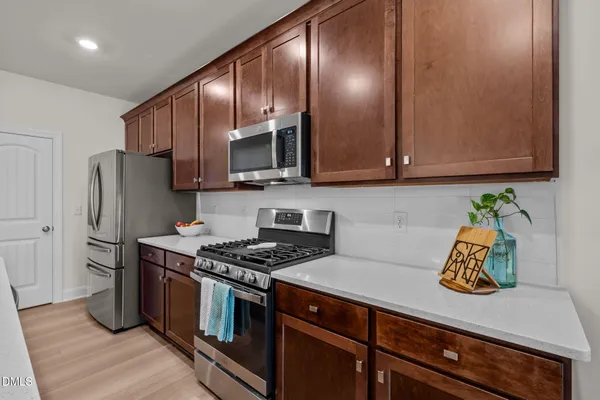 a kitchen with a stove a sink a counter top space and living room view