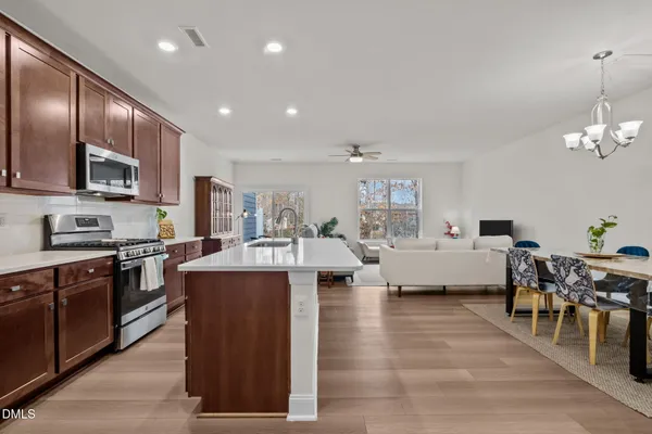 a kitchen with kitchen island granite countertop appliances cabinets sink and wooden floor