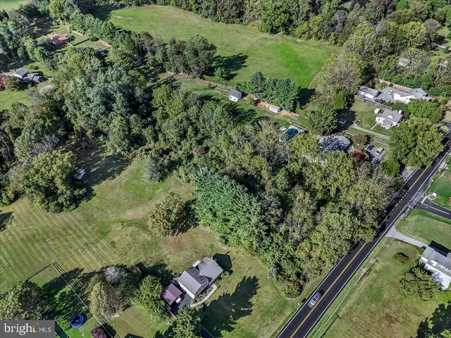 an aerial view of a residential houses with outdoor space and trees