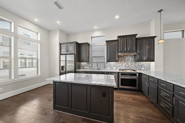 a large kitchen with stainless steel appliances granite countertop a sink stove and refrigerator