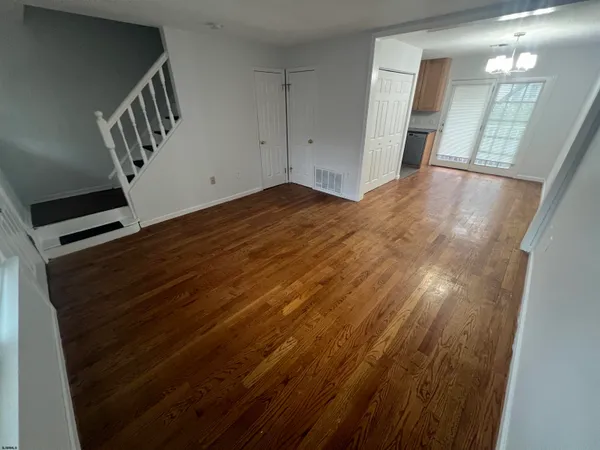 a view of an empty room with wooden floor and staircase