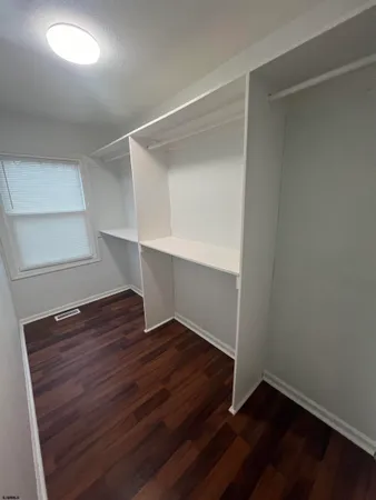 a view of an empty room with wooden floor and closet