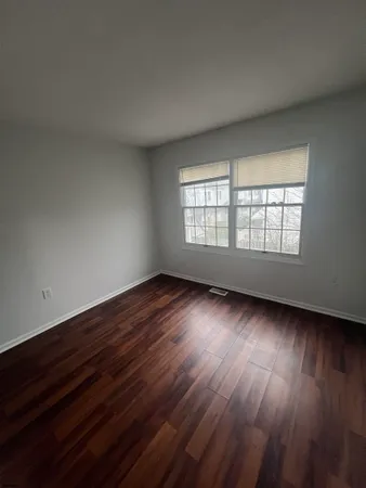 a view of an empty room with wooden floor and window