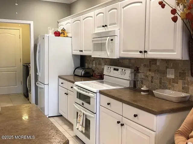 a kitchen with stainless steel appliances granite countertop a refrigerator a stove and white cabinets with wooden floor