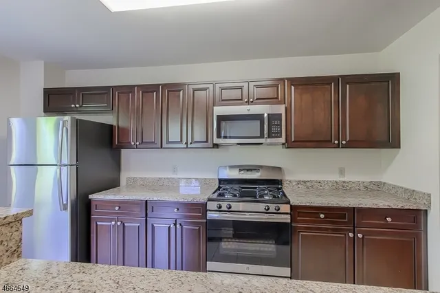 a kitchen with granite countertop a stove microwave and refrigerator