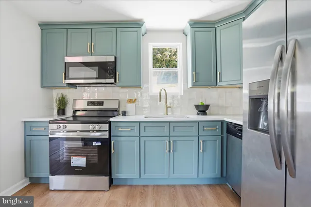 a kitchen with stainless steel appliances granite countertop a stove a sink dishwasher a refrigerator and a microwave oven with wooden floor