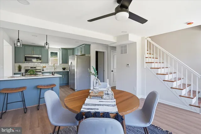 a kitchen with stainless steel appliances a refrigerator a sink dishwasher a stove and white cabinets with wooden floor