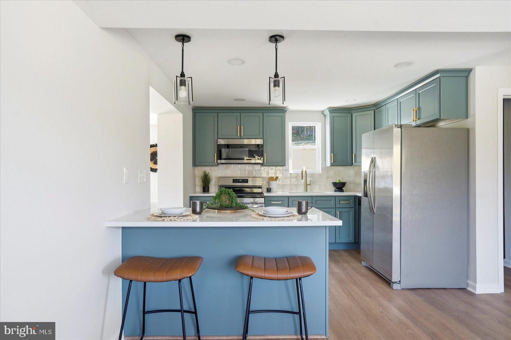 2105 Stringtown Road Sparks Glencoe, MD 21152 - Photo 9 of 57 a kitchen with stainless steel appliances a refrigerator a sink dishwasher a stove and white cabinets with wooden floor