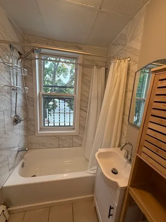 a bathroom with a tub a sink and a large window