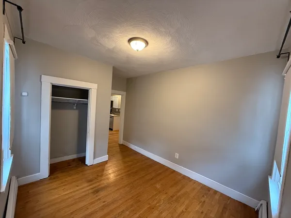 a view of an empty room with wooden floor and closet