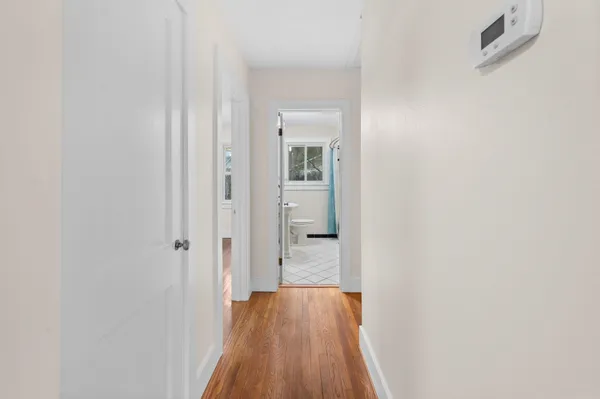 a view of a hallway with wooden floor and a bathroom